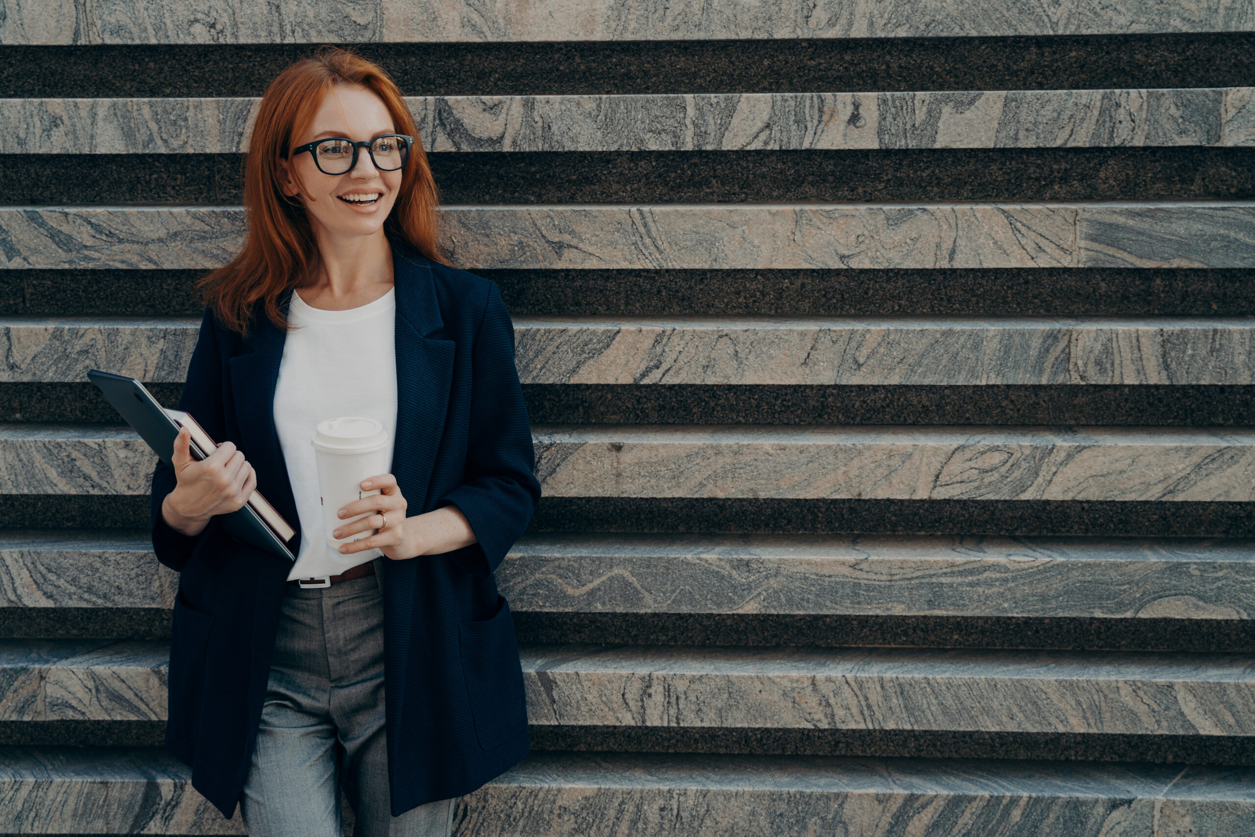 A professional woman holding a tablet and coffee, illustrating how to build a personal brand.