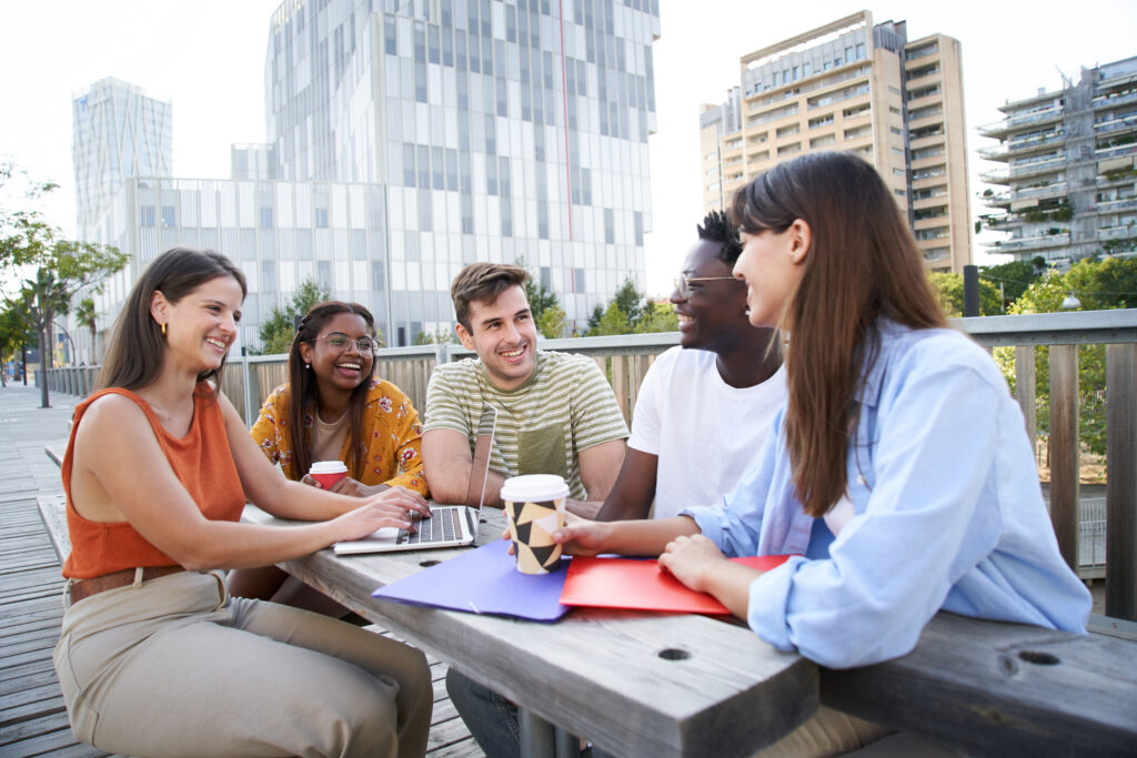 College grads brainstorming together outside, capturing teamwork and growth during a summer internship.